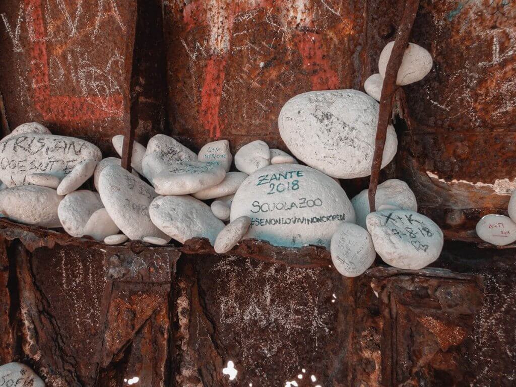 Intriguing rocks with handwritten messages inside the Navagio Beach shipwreck, a hidden gem in Zakynthos.