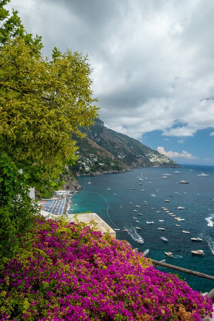 Vibrant bougainvillea flowers against Positano's picturesque setting, symbolizing the lush beauty of the Amalfi Coast for nature lovers visiting from Napoli.
