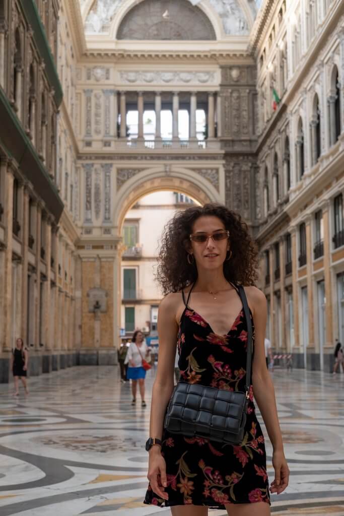 Woman standing inside Galleria Umberto I, Naples, showcasing its stunning architecture.