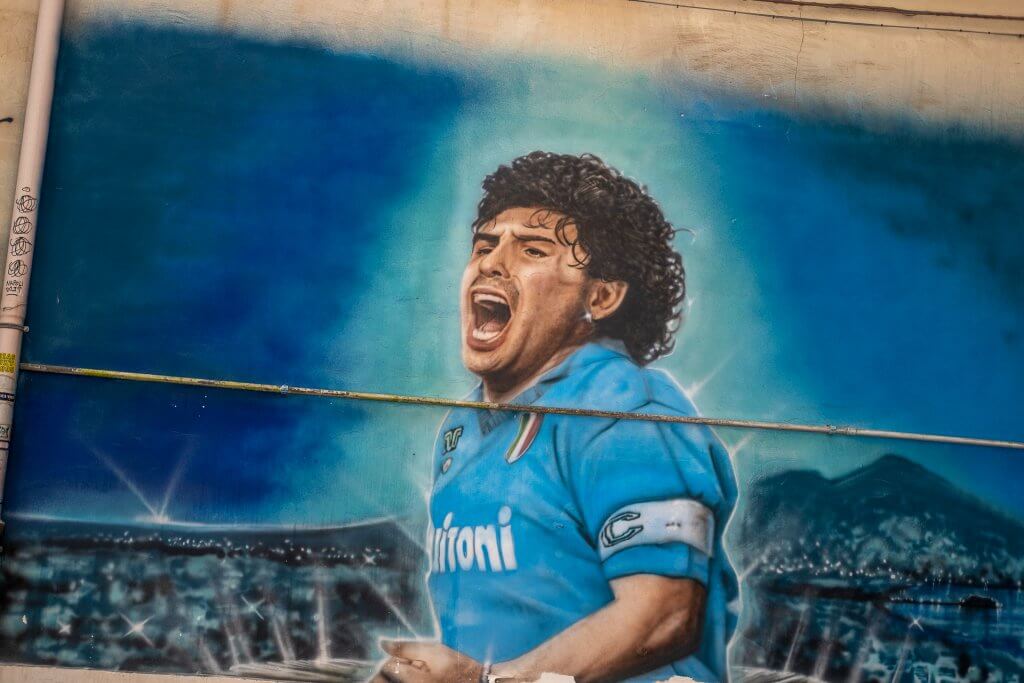 Vibrant Maradona graffiti on Naples street, embodying the city's passion for football, a unique sight for visitors pondering what to do in Napoli.